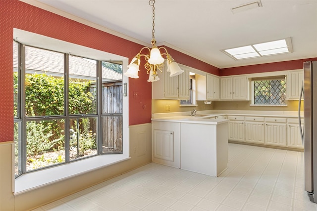 10009 Apple Creek Dr, Dallas, TX 75243 - kitchen with freestanding refrigerator, light countertops, a peninsula, wainscoting, and hanging light fixtures