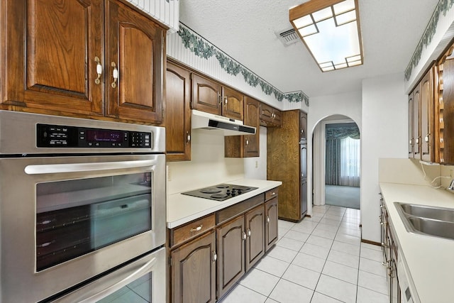 233 Hillview Dr, Hurst, TX 76054 - kitchen with arched walkways, under cabinet range hood, light tile patterned floors, black electric stovetop, and light countertops