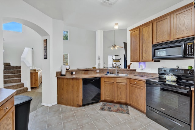 10027 Hanover Dr, Providence Village, TX 76227 - kitchen featuring black appliances, arched walkways, ceiling fan, light tile patterned flooring, and brown cabinetry
