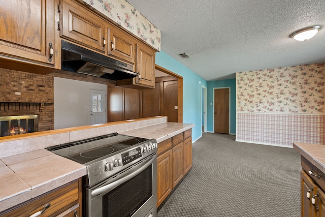 7655 Veal Station Rd, Azle, TX 76020 - kitchen with stainless steel electric stove, wallpapered walls, under cabinet range hood, carpet, and brown cabinets