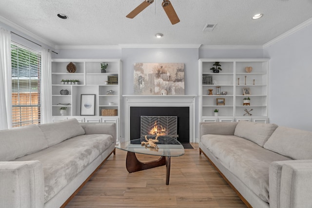 8347 Mountainview Dr, Dallas, TX 75249 - living room with a warm lit fireplace, a textured ceiling, a ceiling fan, wood finished floors, and ornamental molding
