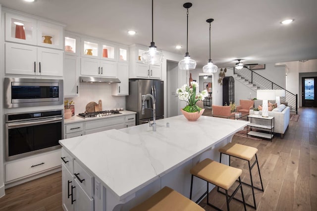 1921 Calumet Dr, Aubrey, TX 76227 - kitchen with stainless steel appliances, white cabinets, a breakfast bar area, dark wood-style flooring, and recessed lighting