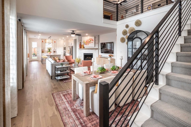 1921 Calumet Dr, Aubrey, TX 76227 - living area with stairs, a ceiling fan, light wood-style flooring, a towering ceiling, and a fireplace