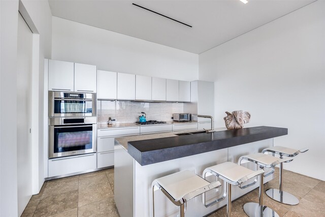1717 Arts Plz Unit 1808, Dallas, TX 75201 - kitchen with a breakfast bar, tasteful backsplash, stainless steel appliances, and white cabinets