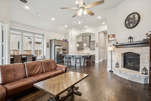 12229 Prudence Dr, Fort Worth, TX 76052 - living area featuring a ceiling fan, arched walkways, dark wood finished floors, vaulted ceiling, and a stone fireplace