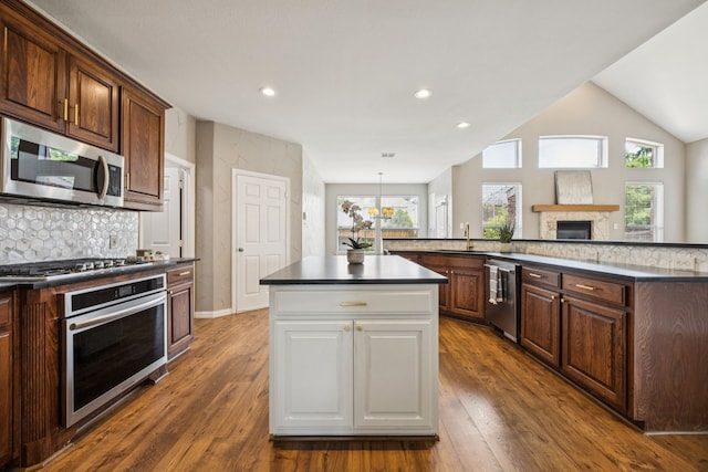 1613 Country Brook Ln, Allen, TX 75002 - kitchen with stainless steel appliances, a center island, dark countertops, a fireplace, and dark wood-style flooring