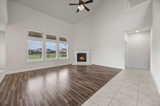 3204 Wimberley Ln, Rockwall, TX 75032 - unfurnished living room with high vaulted ceiling, ceiling fan, a glass covered fireplace, and light wood-style flooring
