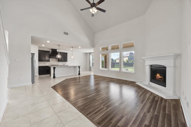 3204 Wimberley Ln, Rockwall, TX 75032 - unfurnished living room featuring a ceiling fan, a glass covered fireplace, light tile patterned floors, high vaulted ceiling, and recessed lighting