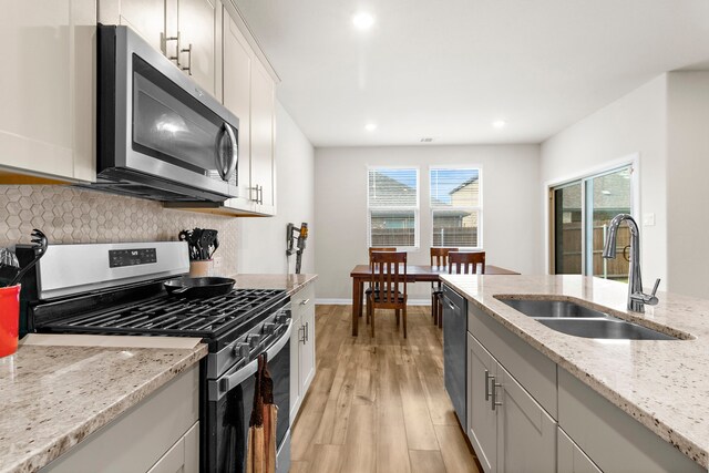 1211 Sweetleaf St, Melissa, TX 75454 - kitchen with appliances with stainless steel finishes, decorative backsplash, light wood-style floors, light stone counters, and recessed lighting