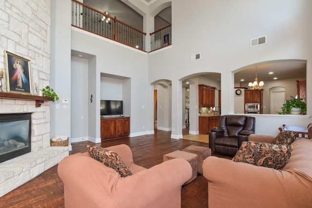 9750 Candlewood Dr, Frisco, TX 75033 - living room with arched walkways, a fireplace, a high ceiling, dark wood-style floors, and a chandelier