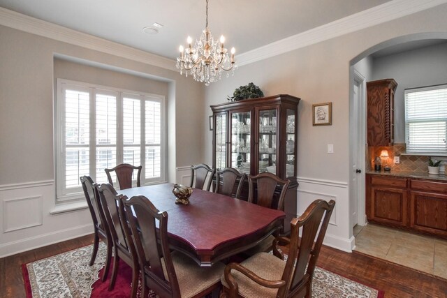 9750 Candlewood Dr, Frisco, TX 75033 - dining area featuring arched walkways, a chandelier, wood finished floors, and ornamental molding