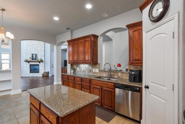 9750 Candlewood Dr, Frisco, TX 75033 - kitchen with stainless steel dishwasher, arched walkways, tasteful backsplash, light tile patterned floors, and a kitchen island
