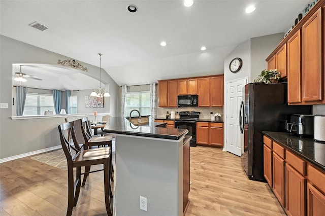 9210 Wild River Dr, Arlington, TX 76002 - kitchen featuring black appliances, light wood-style floors, a kitchen breakfast bar, brown cabinets, and lofted ceiling
