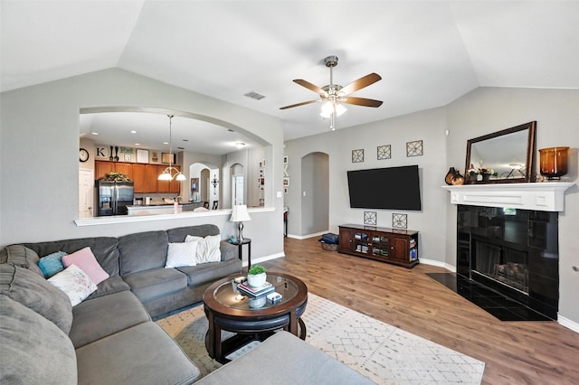 9210 Wild River Dr, Arlington, TX 76002 - living room with arched walkways, lofted ceiling, a ceiling fan, wood finished floors, and a tile fireplace
