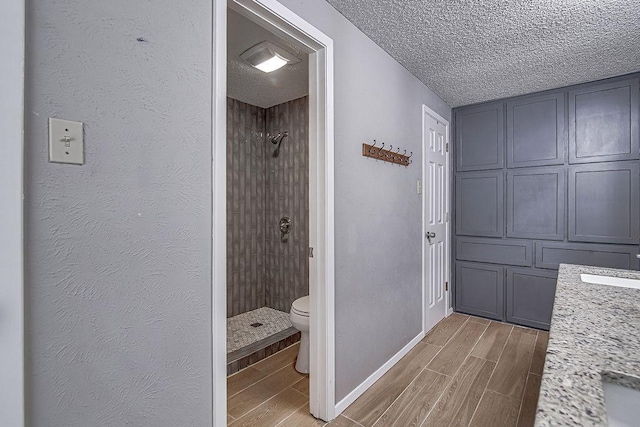 5800 Thoreau Ln, Arlington, TX 76016 - full bathroom with wood tiled floors, a shower stall, and a textured ceiling