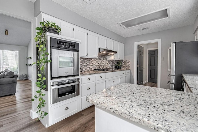 5800 Thoreau Ln, Arlington, TX 76016 - kitchen featuring appliances with stainless steel finishes, a textured ceiling, white cabinetry, tasteful backsplash, and light stone countertops
