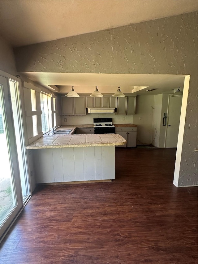416 Meadowhill Dr, Garland, TX 75043 - kitchen featuring a textured wall, gas range oven, vaulted ceiling, a peninsula, and under cabinet range hood