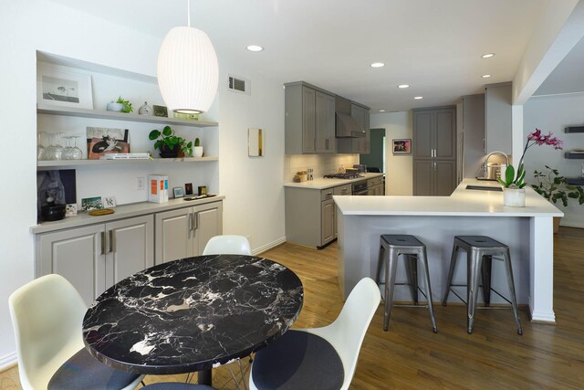 4232 Meadowdale Ln, Dallas, TX 75229 - kitchen with gray cabinetry, light wood-type flooring, a kitchen breakfast bar, custom range hood, and recessed lighting