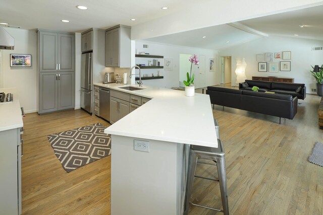 4232 Meadowdale Ln, Dallas, TX 75229 - kitchen featuring gray cabinets, a peninsula, appliances with stainless steel finishes, light wood finished floors, and light countertops