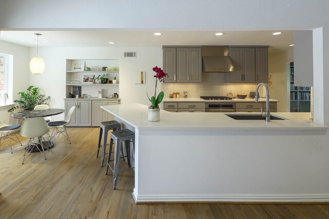 4232 Meadowdale Ln, Dallas, TX 75229 - kitchen featuring wall chimney exhaust hood, appliances with stainless steel finishes, light countertops, light wood-style flooring, and recessed lighting