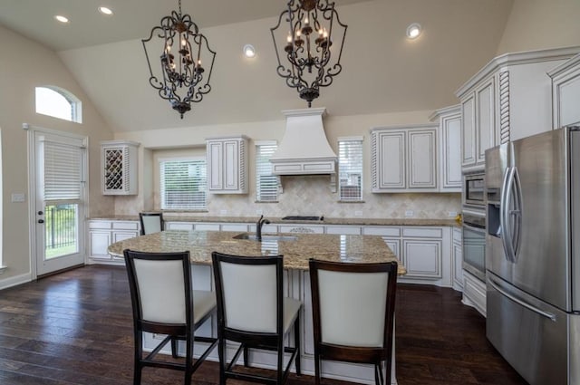 6812 S Fork Dr, North Richland Hills, TX 76182 - kitchen featuring stainless steel appliances, custom exhaust hood, vaulted ceiling, dark wood-style flooring, and an island with sink