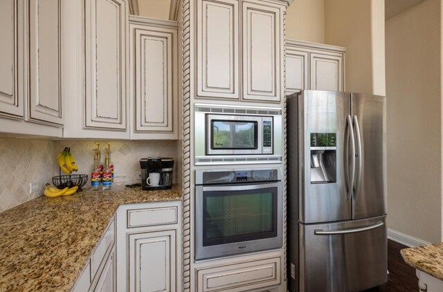 6812 S Fork Dr, North Richland Hills, TX 76182 - kitchen with appliances with stainless steel finishes, backsplash, light stone counters, and dark wood-type flooring