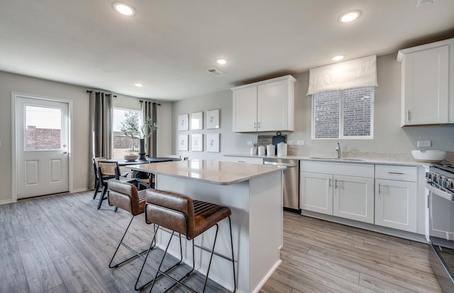7518 Fenton Pkwy, Pilot Point, TX 76258 - kitchen featuring dishwasher, a breakfast bar area, white cabinets, stove, and recessed lighting