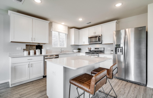 7518 Fenton Pkwy, Pilot Point, TX 76258 - kitchen featuring appliances with stainless steel finishes, white cabinetry, light wood-style floors, light countertops, and a center island