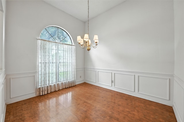 2116 S Winding Creek Dr, Grapevine, TX 76051 - empty room featuring a decorative wall, a chandelier, a wainscoted wall, vaulted ceiling, and wood finished floors