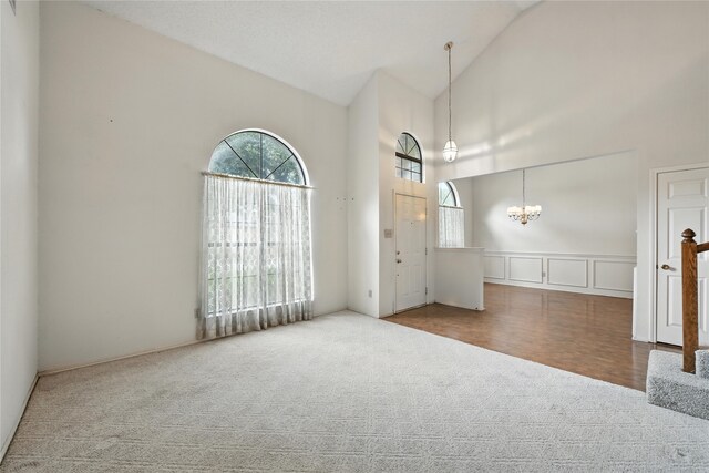 2116 S Winding Creek Dr, Grapevine, TX 76051 - spare room featuring carpet, a chandelier, a decorative wall, high vaulted ceiling, and a wainscoted wall