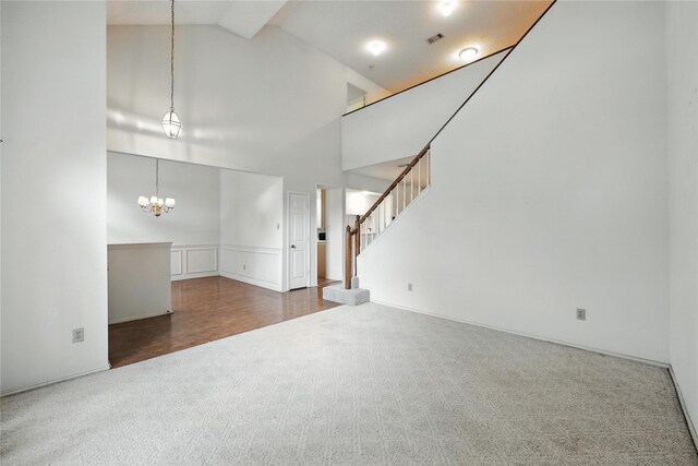 2116 S Winding Creek Dr, Grapevine, TX 76051 - unfurnished living room featuring carpet, a chandelier, high vaulted ceiling, stairway, and a wainscoted wall