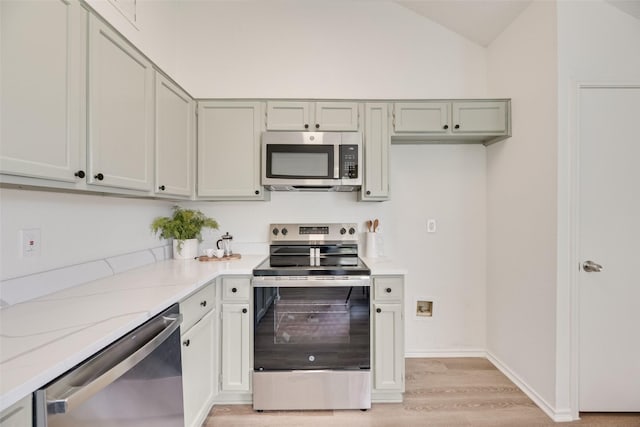 552 Kirkland Dr, Coppell, TX 75019 - kitchen featuring appliances with stainless steel finishes, light wood-style floors, vaulted ceiling, and light stone counters