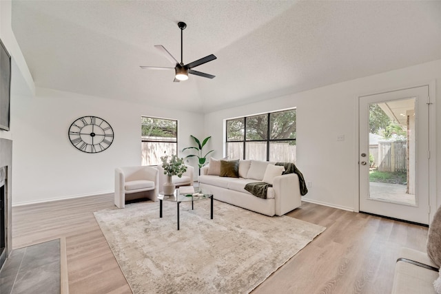 552 Kirkland Dr, Coppell, TX 75019 - living area with ceiling fan, light wood-style floors, lofted ceiling, a fireplace with flush hearth, and a textured ceiling