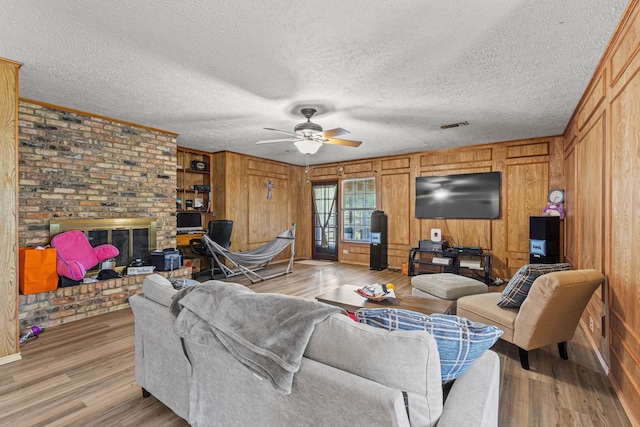 567 Celtic Rd, Howe, TX 75459 - living area with ceiling fan, light wood-type flooring, a fireplace, wood walls, and ornamental molding