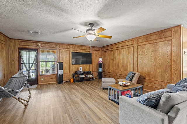 567 Celtic Rd, Howe, TX 75459 - living room featuring light wood finished floors, a ceiling fan, a textured ceiling, and wooden walls