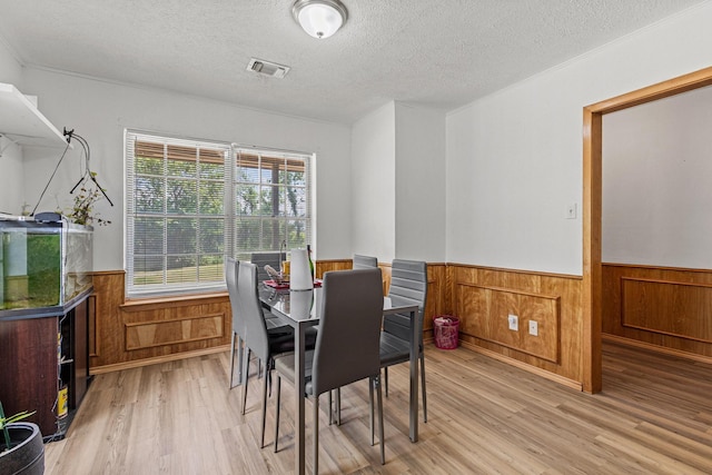 567 Celtic Rd, Howe, TX 75459 - dining area with a wainscoted wall, light wood-style flooring, a textured ceiling, and wooden walls
