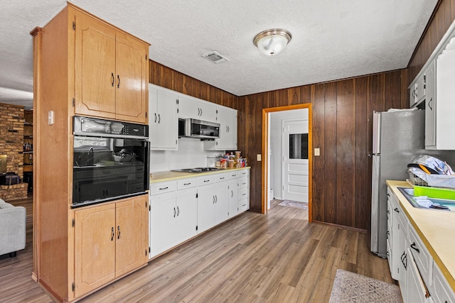 567 Celtic Rd, Howe, TX 75459 - kitchen with black appliances, a textured ceiling, light countertops, light wood-style floors, and wooden walls