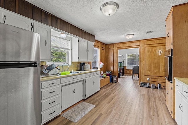 567 Celtic Rd, Howe, TX 75459 - kitchen with freestanding refrigerator, light countertops, light wood-style flooring, a textured ceiling, and healthy amount of natural light