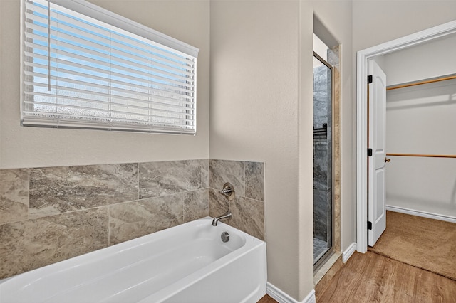 515 W Broad St, Pilot Point, TX 76258 - bathroom featuring a bath, a walk in closet, plenty of natural light, and wood finished floors