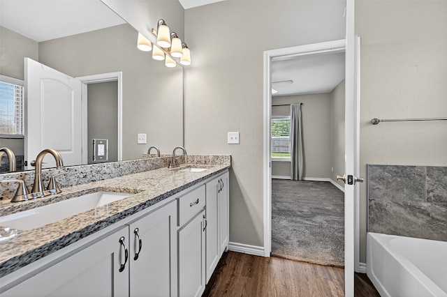 515 W Broad St, Pilot Point, TX 76258 - bathroom featuring double vanity, a bath, wood finished floors, and a chandelier