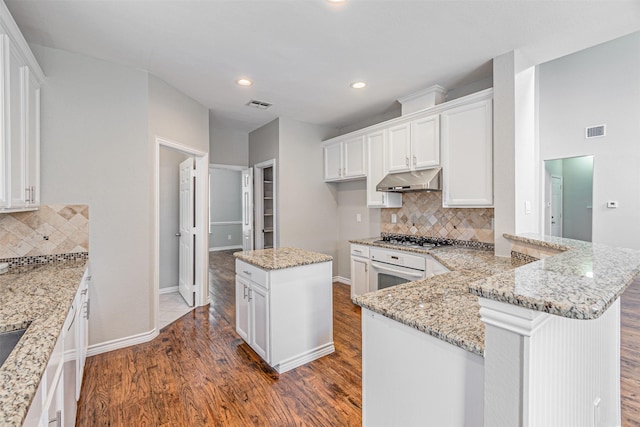 1900 Sumac Dr, Flower Mound, TX 75028 - kitchen featuring white oven, under cabinet range hood, stainless steel gas stovetop, wood finished floors, and white cabinets