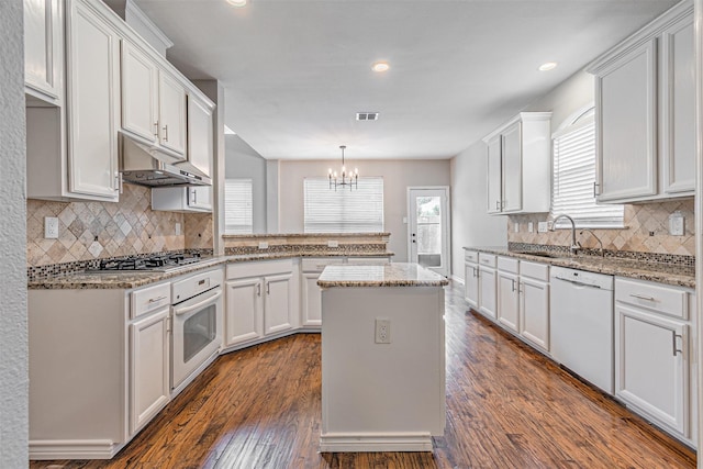 1900 Sumac Dr, Flower Mound, TX 75028 - kitchen featuring white appliances, under cabinet range hood, a peninsula, a chandelier, and white cabinets
