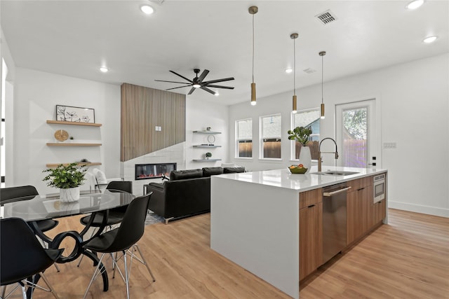 404 Cleaves St, Dallas, TX 75203 - kitchen featuring appliances with stainless steel finishes, a fireplace, modern cabinets, ceiling fan, and light wood finished floors