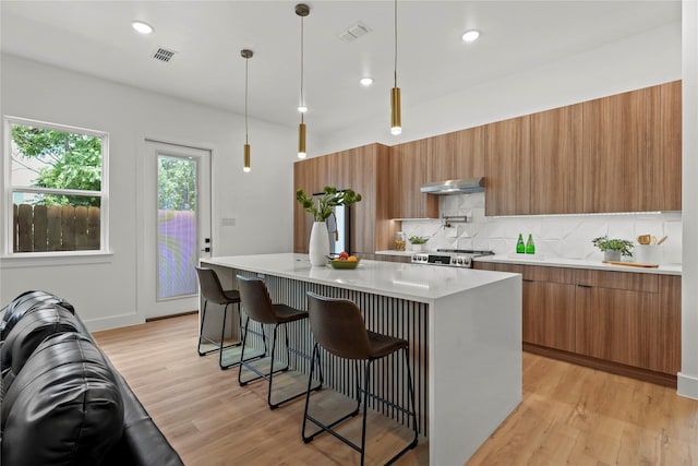 404 Cleaves St, Dallas, TX 75203 - kitchen with modern cabinets, brown cabinetry, under cabinet range hood, light countertops, and decorative backsplash