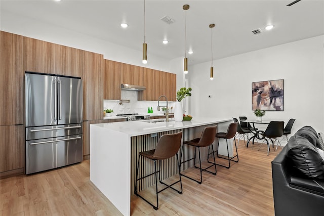 404 Cleaves St, Dallas, TX 75203 - kitchen with freestanding refrigerator, modern cabinets, brown cabinets, under cabinet range hood, and light wood-style floors