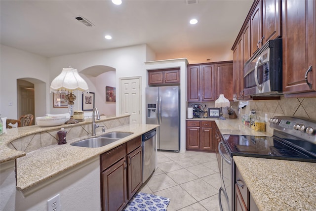 508 Hummingbird Dr, Little Elm, TX 75068 - kitchen featuring stainless steel appliances, arched walkways, tasteful backsplash, recessed lighting, and light tile patterned floors