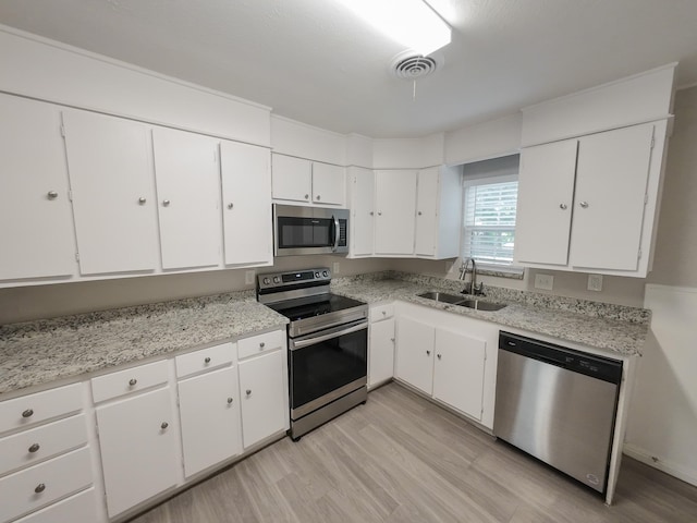 904 Forrestal Dr, Arlington, TX 76010 - kitchen with appliances with stainless steel finishes, white cabinets, light countertops, and light wood finished floors