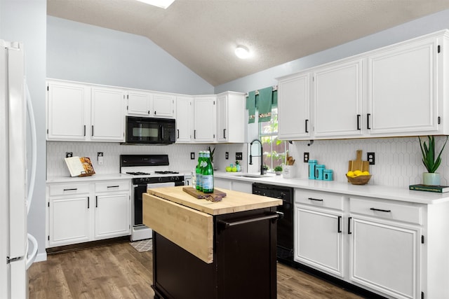 2073 Rushmore Ct, Lewisville, TX 75067 - kitchen featuring black appliances, vaulted ceiling, white cabinets, tasteful backsplash, and a center island