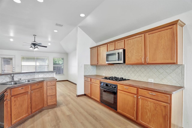 1629 Lakeside Dr, Allen, TX 75002 - kitchen with black oven, stainless steel microwave, vaulted ceiling, gas cooktop, and light wood-style flooring