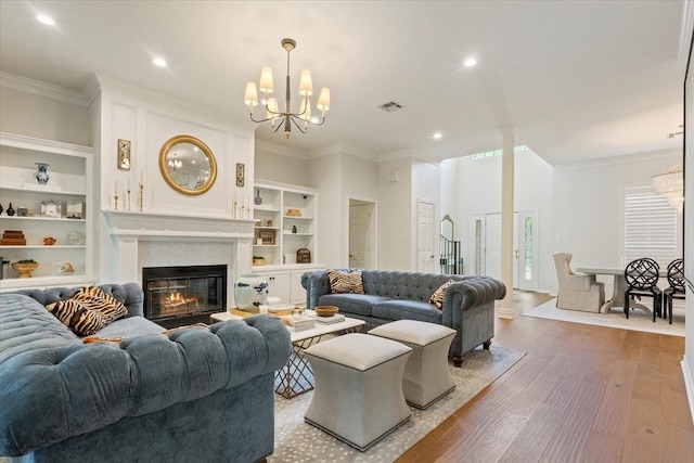 10003 Willow Bend Dr, Woodway, TX 76712 - living room featuring built in features, a chandelier, wood finished floors, crown molding, and a glass covered fireplace